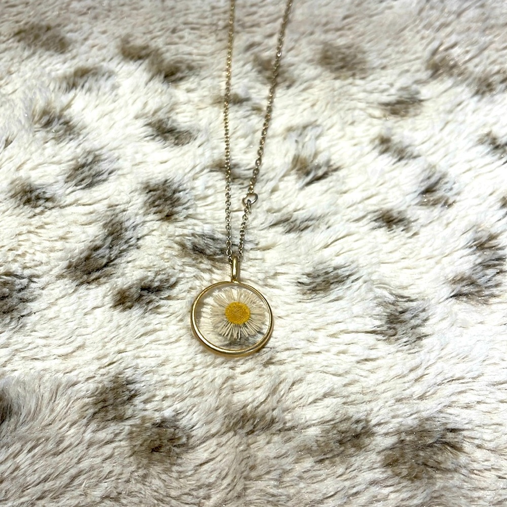 Long gold necklace with pressed daisy pendant, hits below bust